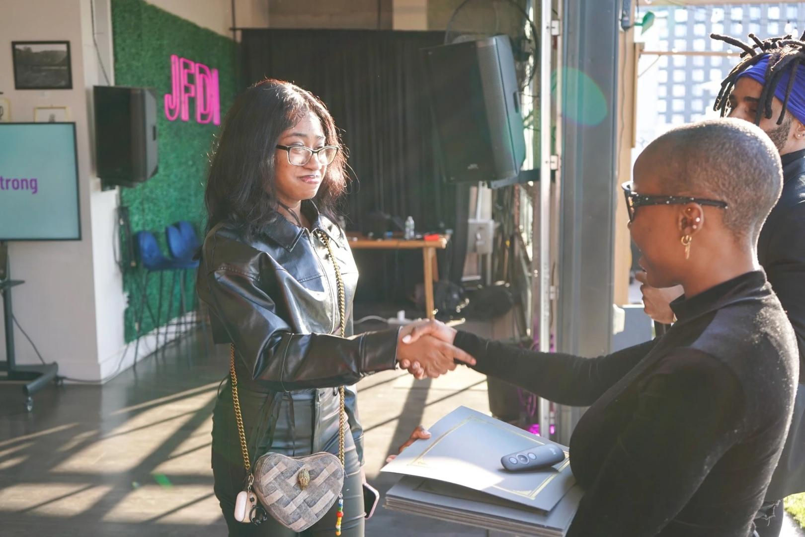 A fellow receiving a certificate with a handshake